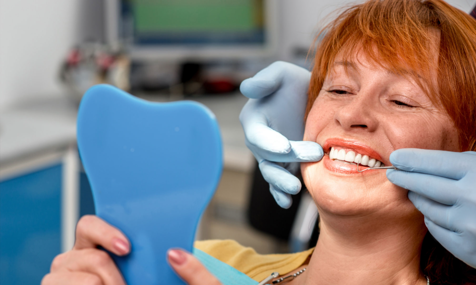 patient looking in the mirror smiling after frenectomy treatment