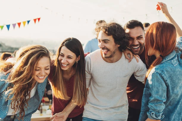Group of friends laughing joyfully outdoors, capturing how smiling and laughter foster social connection and boost mental and physical health—as highlighted in the blog.