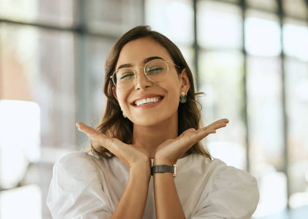 Confident young woman smiling with hands framing her face, illustrating the positive emotional and social effects of feeling good about your smile, thanks to healthy gums and gums.